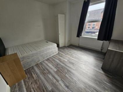A bright, clean single bedroom featuring wood-e...