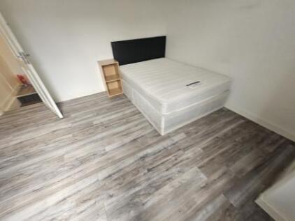 A tidy single bedroom with modern wood-effect f...
