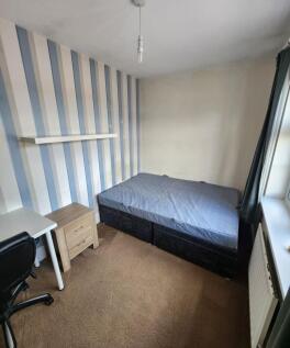 A cozy single bedroom featuring a neatly made b...