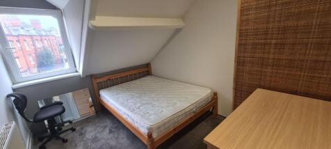 A cozy single bedroom featuring a comfortable b...