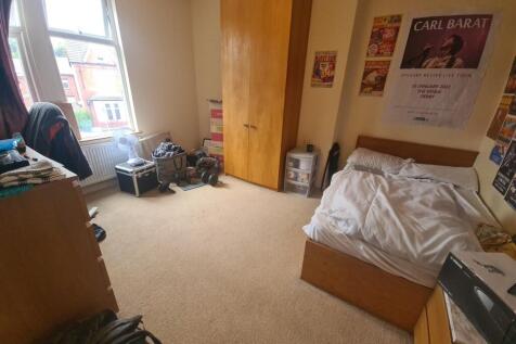 A cozy single bedroom featuring a large window ...