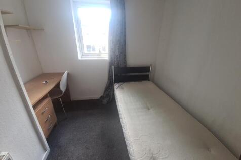 A compact bedroom featuring a single bed with a...