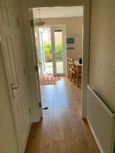 A bright hallway with warm wooden flooring lead...
