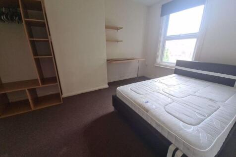 A bright double bedroom featuring a large windo...