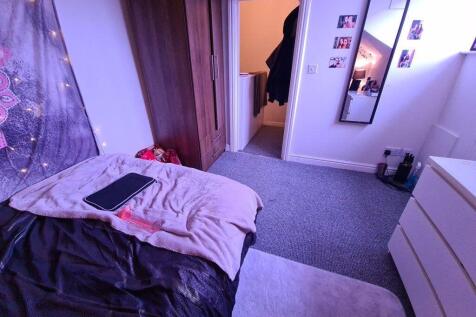 A cozy single bedroom featuring a bed with soft...