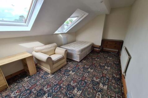 A cozy attic bedroom featuring a single bed, a ...