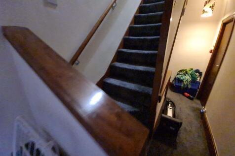 A narrow hallway with a carpeted staircase and ...