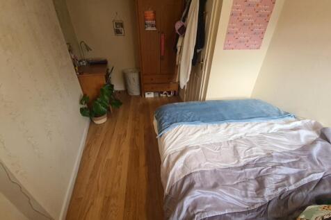 A tidy and cozy single bedroom featuring wooden...