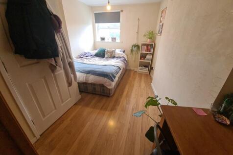 A cozy single bedroom with a wooden floor, a be...