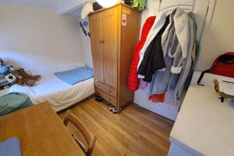 A cozy single bedroom featuring a neatly made s...