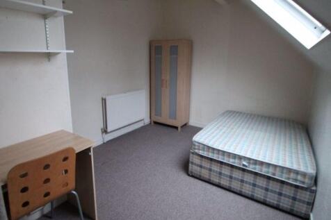 A neat single bedroom featuring a cozy bed unde...