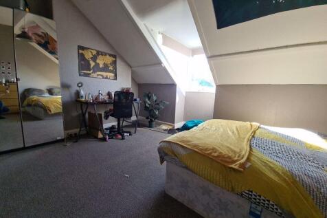 A cozy single bedroom featuring a large skyligh...