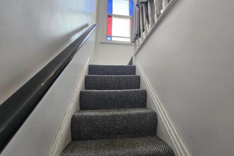 Carpeted staircase with clean white walls and a...