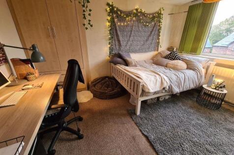 A cozy single bedroom with a neatly made bed, a...
