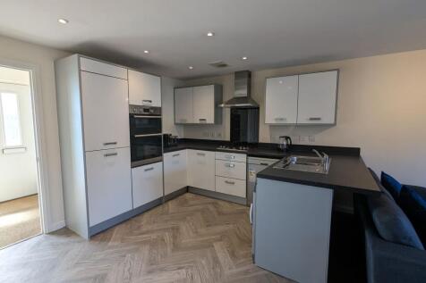 Modern kitchen featuring sleek white cabinets a...