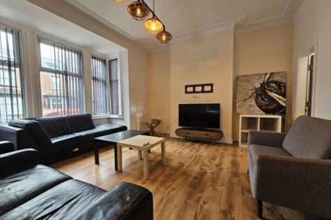 A well-lit living room featuring three sofas ar...