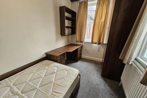 A cozy single bedroom featuring a comfortable b...