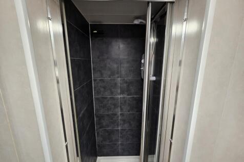 A modern shower space with sleek dark gray tile...