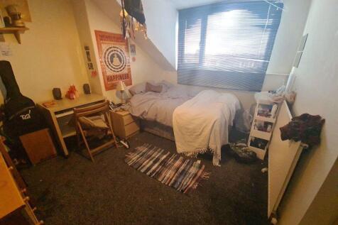 A cozy single bedroom featuring a comfortable b...