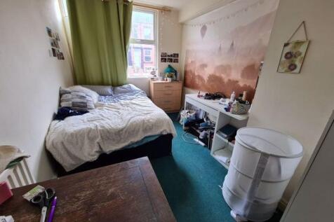 A cozy single bedroom featuring a comfortable b...