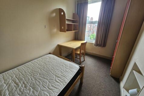 A cozy single bedroom featuring a comfortable b...