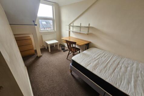 A cozy single bedroom featuring a neatly made b...