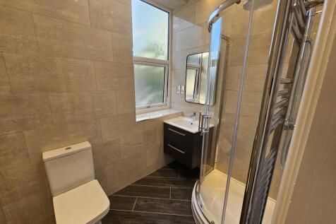 A modern bathroom suite featuring a curved glas...