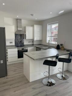 A modern kitchen featuring sleek white cabinetr...