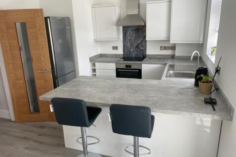 Modern kitchen featuring sleek white cabinetry ...