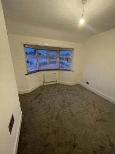 A clean and freshly carpeted single bedroom fea...