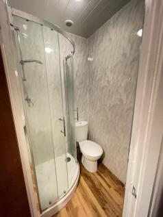 A compact modern bathroom featuring a curved gl...
