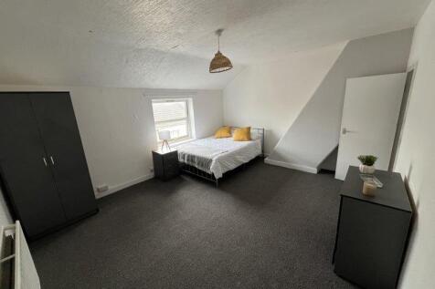 A spacious double bedroom featuring a neatly ma...