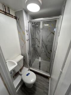 A compact bathroom featuring a modern shower en...