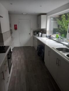 A modern kitchen featuring sleek white cabinets...