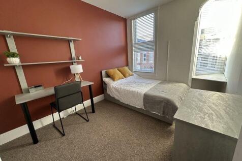 A bright and cozy single bedroom featuring warm...