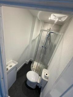 A compact bathroom featuring a modern corner sh...