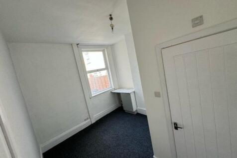 A clean, simple single bedroom featuring a wind...