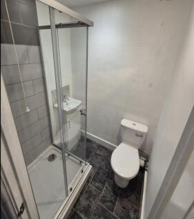A compact bathroom featuring a modern glass-enc...