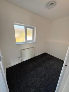 A cozy single bedroom featuring fresh white wal...