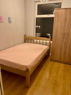 Cozy single bedroom with a wooden bed frame and...