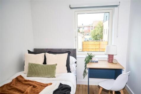 A bright and cozy single bedroom featuring a ne...