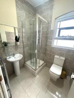 A bright, modern bathroom featuring a corner sh...