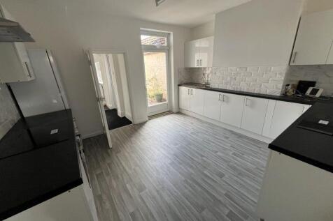 A spacious, modern kitchen with sleek white cab...