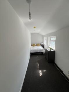 A narrow double bedroom featuring white walls a...