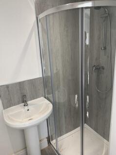 A modern bathroom featuring a corner glass show...
