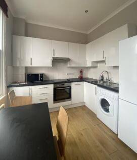 Modern kitchen featuring sleek white cabinetry,...