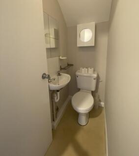 Compact and clean toilet space featuring a whit...