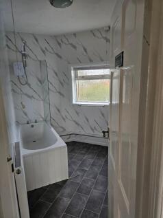 A modern bathroom suite featuring a white batht...