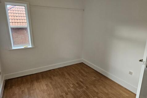 A modest empty single bedroom with wooden floor...