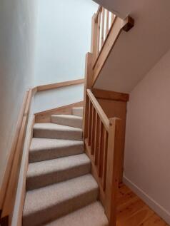A neat, carpeted staircase with wooden railings...